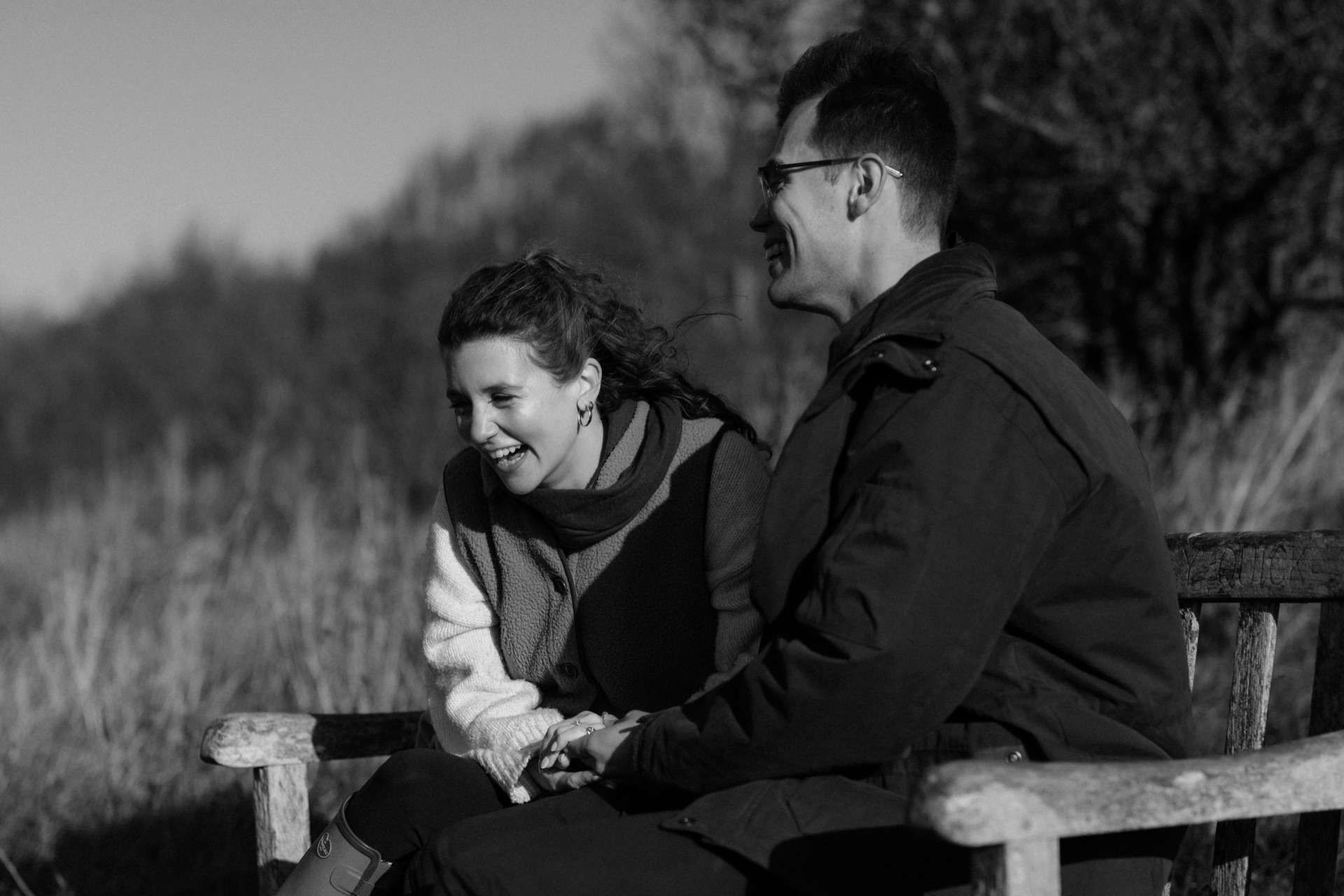 Ella and Vere laughing together on a bench, in black and white