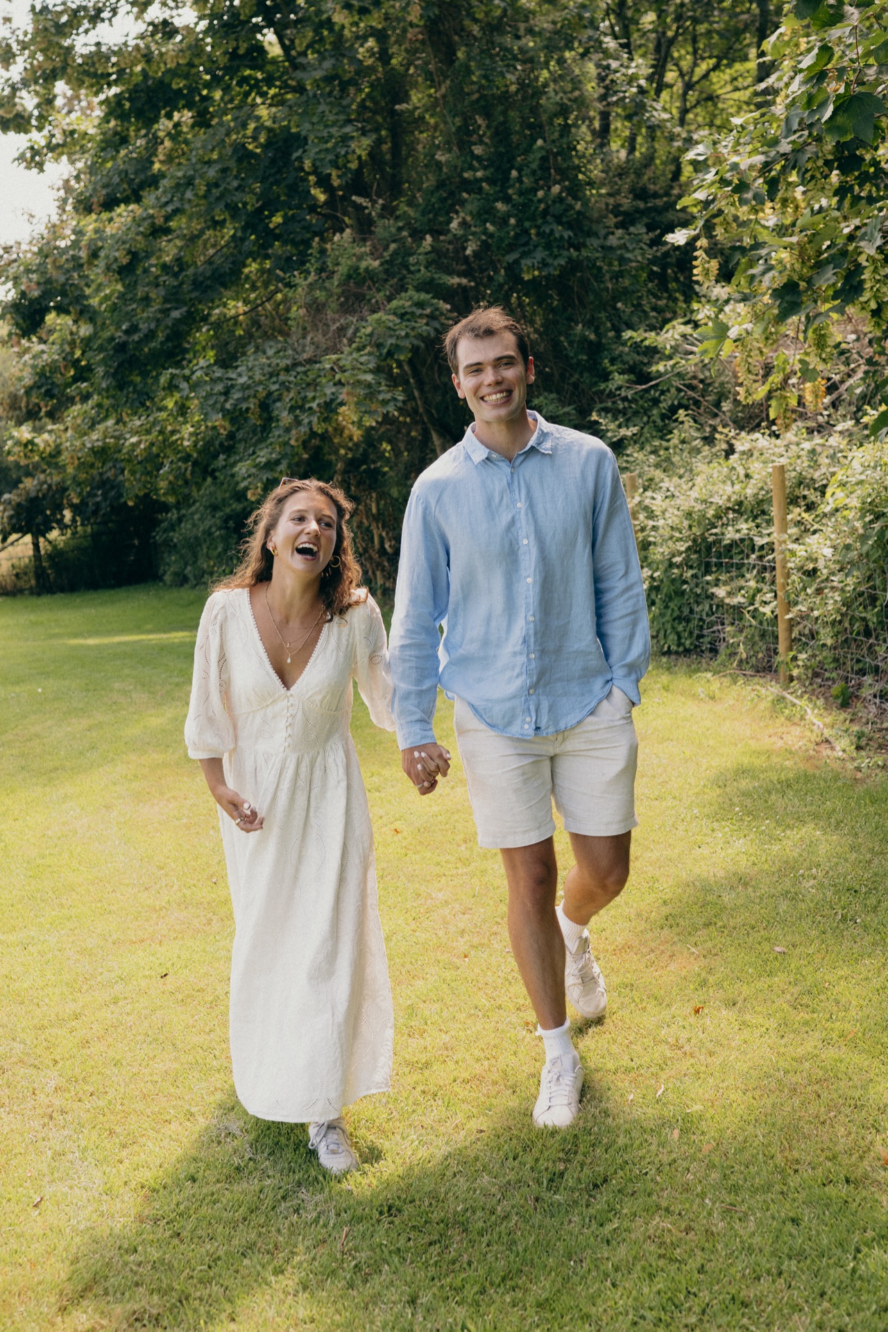 Ella and Vere walking hand in hand across a summer field